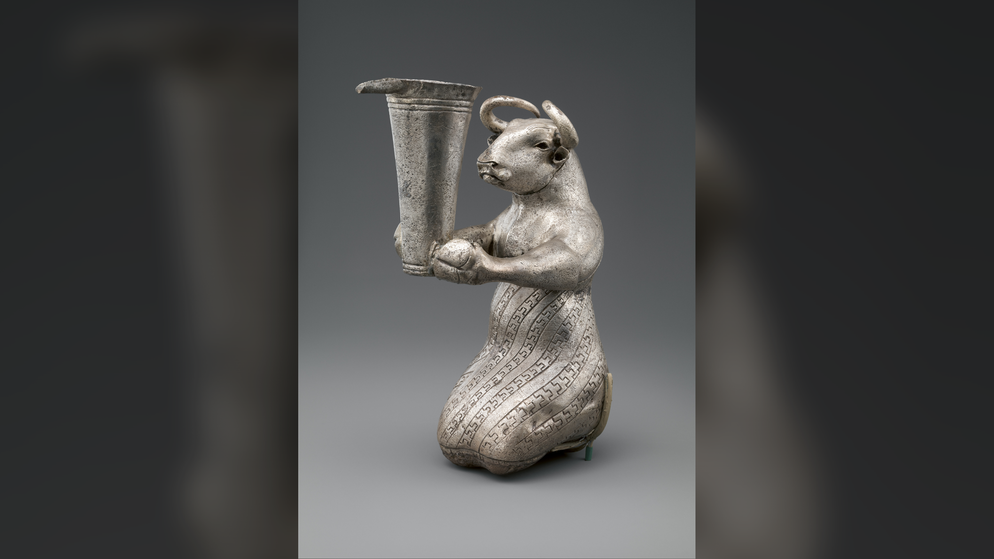 silver human-like bull holding a vessel